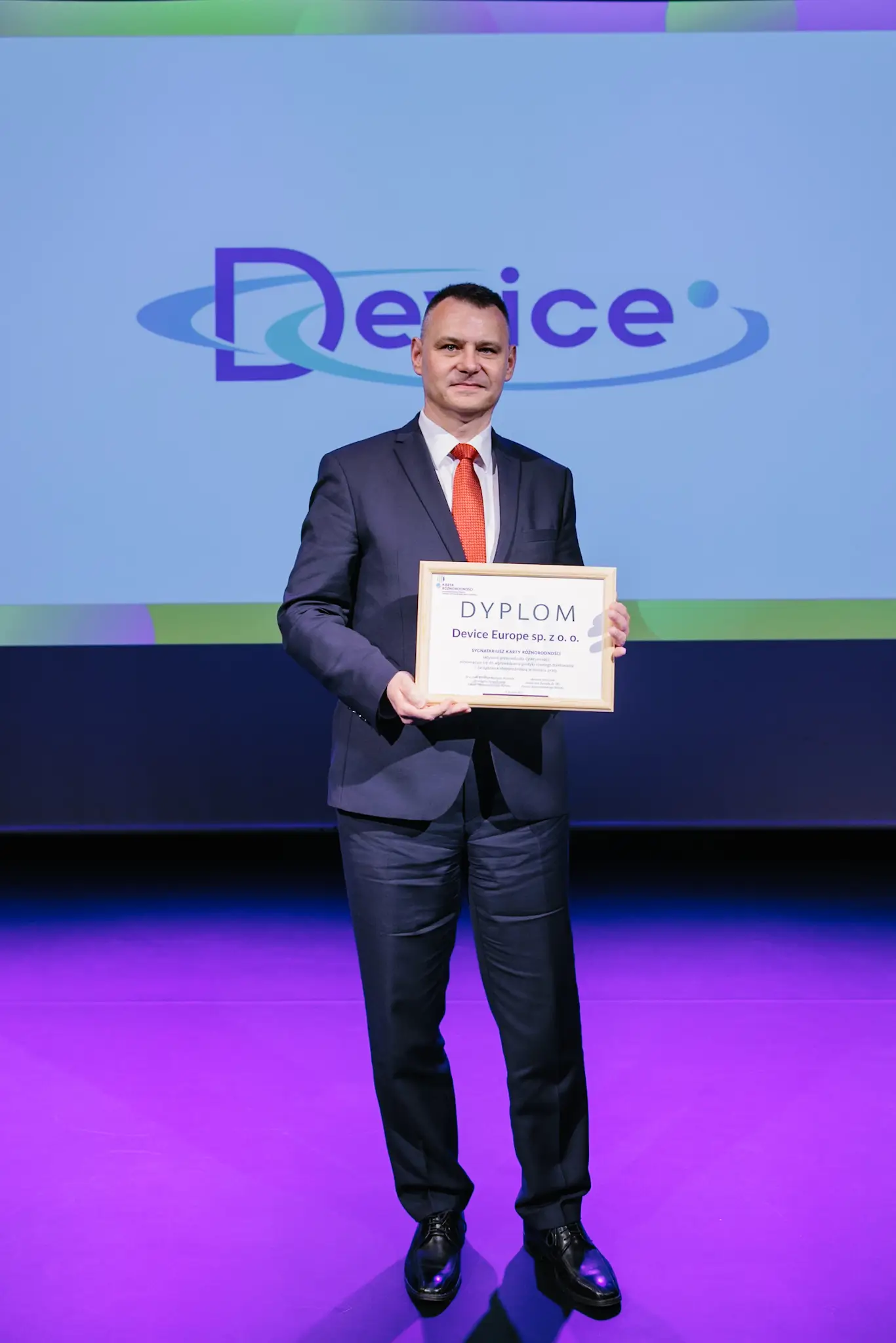 Device Europe representative holding the Diversity IN Check diploma on stage